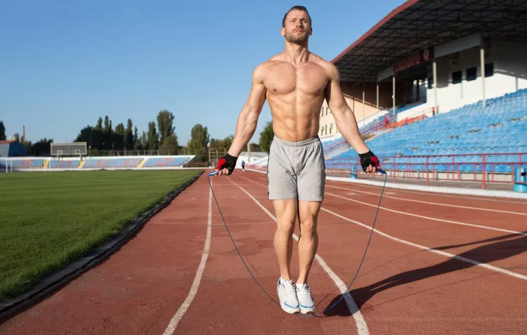 Homme sautant à la corde sur une piste de course 